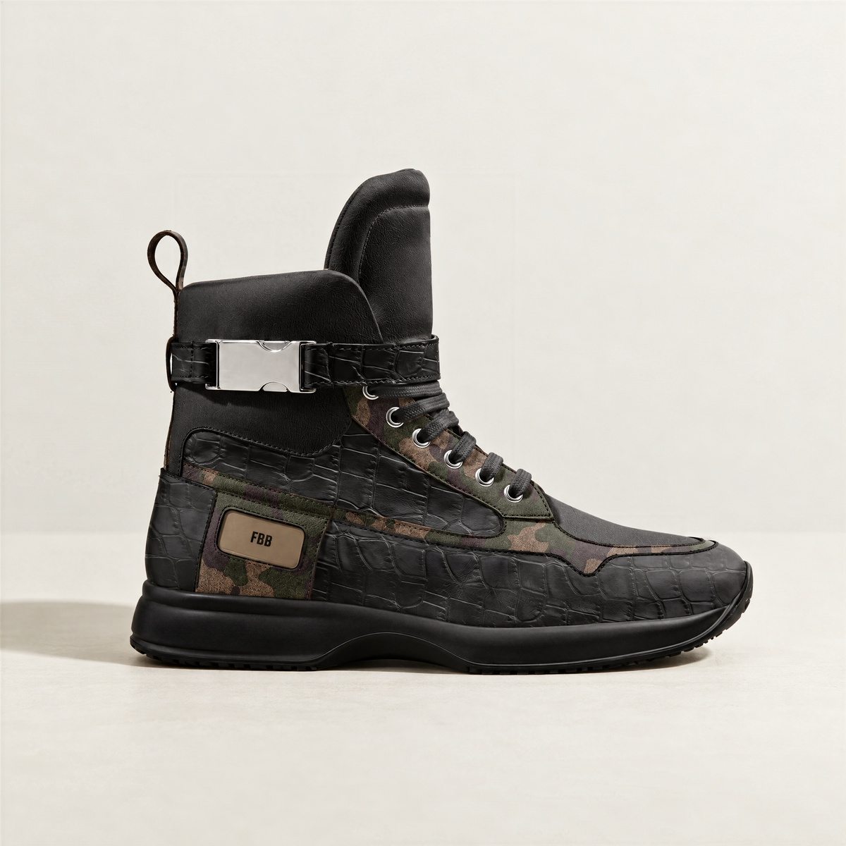 A single high-top sneaker in black textured italian leather and italian suede with camouflage panels, a silver buckle strap, and a tan 'FBB' label on the side, photographed against a light off-white background.