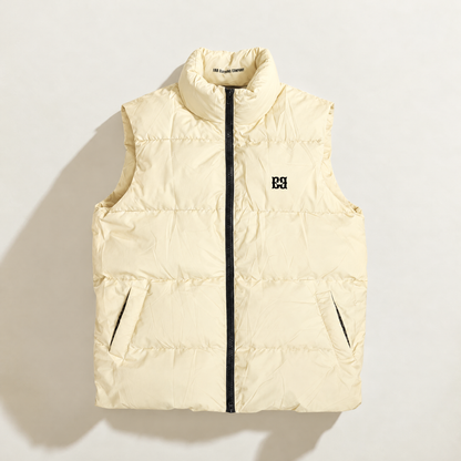 A sleeveless quilted down puffer vest in vanilla cream, featuring a black front zipper, a stand-up collar, and a small black logo on the left chest, displayed against a solid white background.