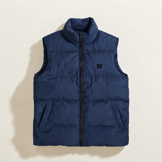 A navy blue down puffer vest with a high collar, front zipper, and a small black monogram logo on the left chest, displayed flat against a light beige background.