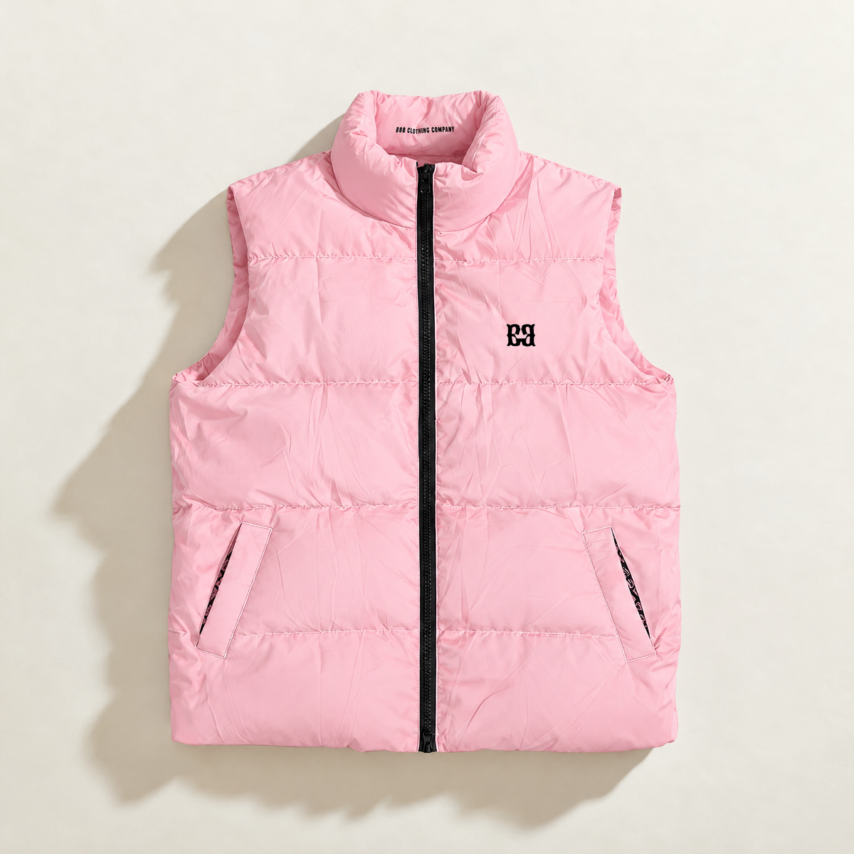 Front of the pink FBB Barrier puffer vest with a black zipper, high collar, side pockets and black FBB chest monogram.
