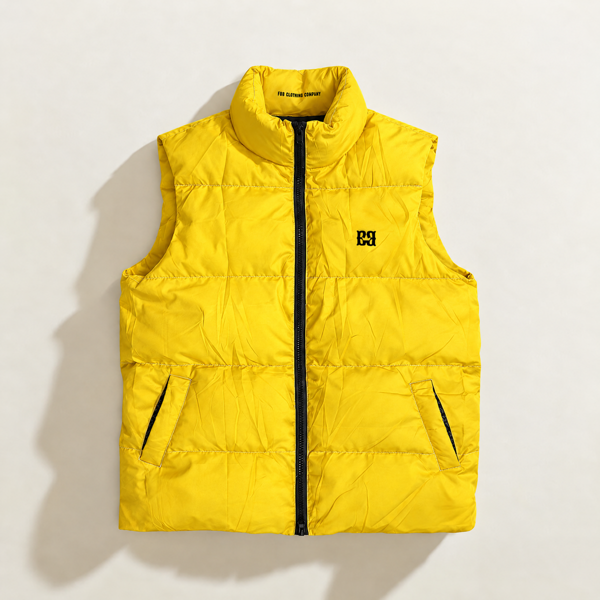 Front of the yellow FBB Barrier puffer vest with a black zipper, high collar, side pockets and black FBB chest monogram.

