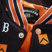 Varsity jacket with brown, orange, and white design on a gray surface | FBB M3 VARSITY One‑of‑One Collector’s Edition